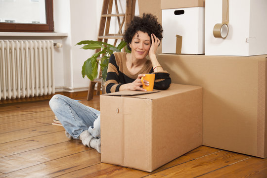 A cheerful woman taking a coffee break while moving house