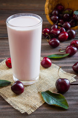 Cherry milk in a glass on wooden background