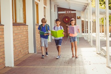 School kids reading books while walking in corridor