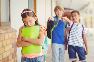 School friends bullying a sad girl in corridor