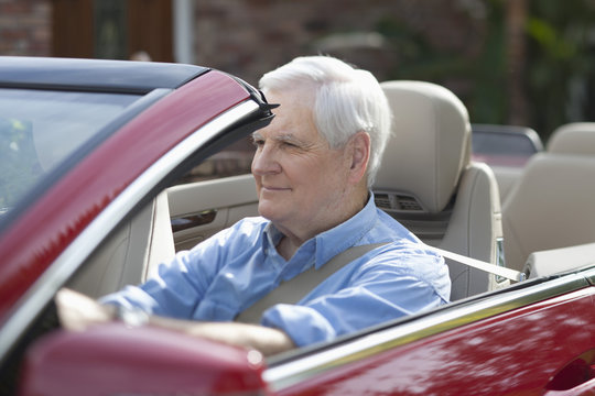 A senior man driving a convertible sports car