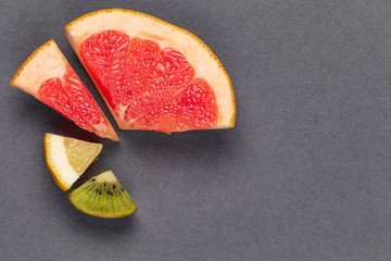 Pie chart of fresh vitamin fruit on gray textural background. Background with space for text....