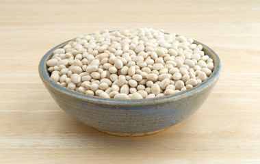 Full bowl of organic navy beans on a wood table