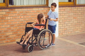 Schoolboy talking to a girl on wheelchair
