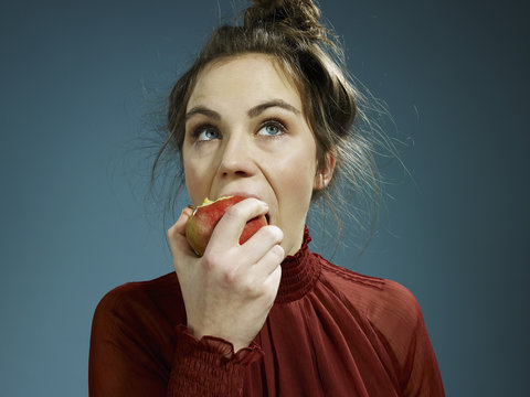 A young hip woman eating an apple