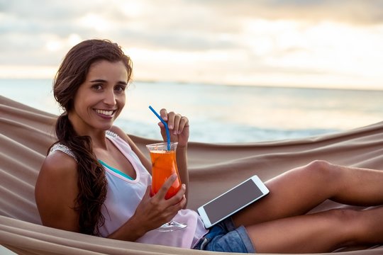 Portrait Of Woman Holding Mocktail While Relaxing On A Hammock