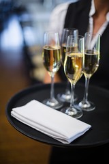 Mid section of waitress holding tray with champagne