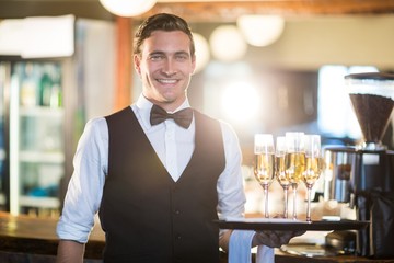 Portrait of waiter holding serving tray with champagne flutes 