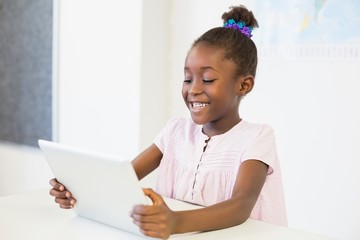 Schoolgirl using digital tablet in classroom