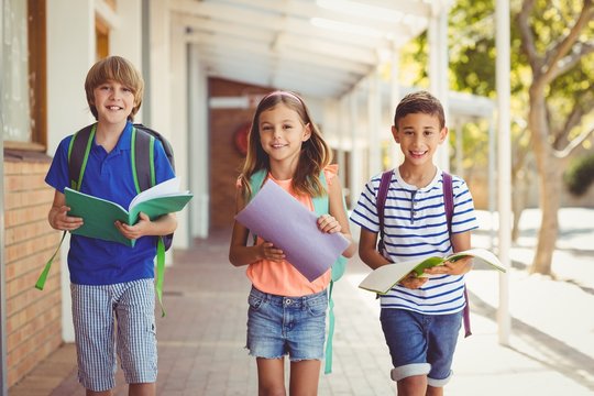 Portrait of smiling school kids standing in school corridor 
