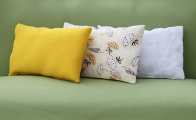 Three pillows on green sofa