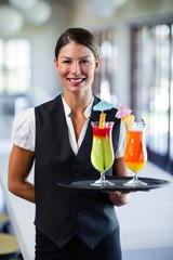 Portrait of smiling waitress serving cocktail 