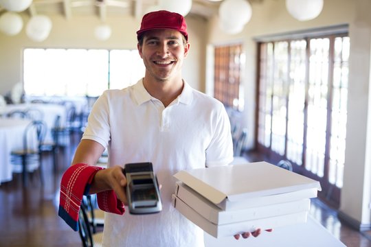 Happy pizza delivery man showing credit card machine
