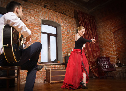 Young woman dancing flamenco and a man playing the guitar