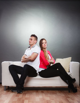 Young couple after quarrel sitting on sofa back to back