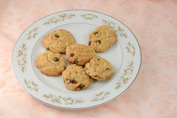 Chocolate chip cookies on white plate on tablecloth