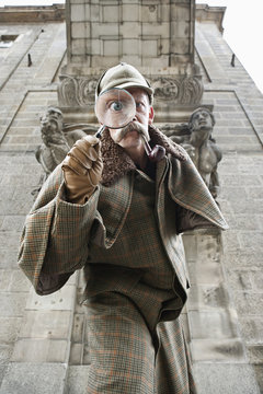 A man dressed up as Sherlock Holmes with a magnifying glass distorting his eye