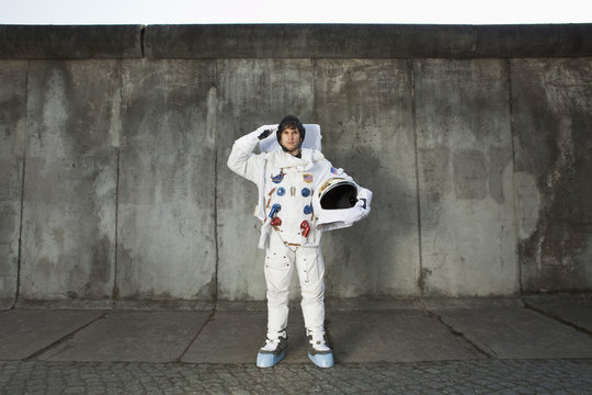 A saluting astronaut standing on a sidewalk in a city