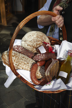 A woman holding a basket of sausages and bread, focus on basket, Carinthia, Austria
