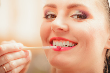 Make up artist applying lipstick with brush.