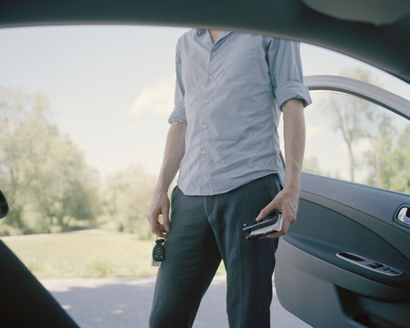 Mid section of man standing near open car door