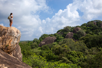 Woman backpacker and photo camera hiking in the mountain peak