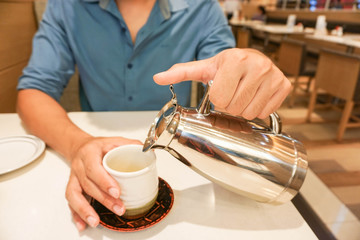 Fototapeta na wymiar A man is pouring hot tea