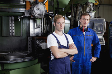 Portrait of two manual workers in a metal parts factory