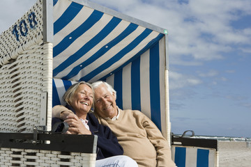 A senior couple sitting together in a hooded beach chair