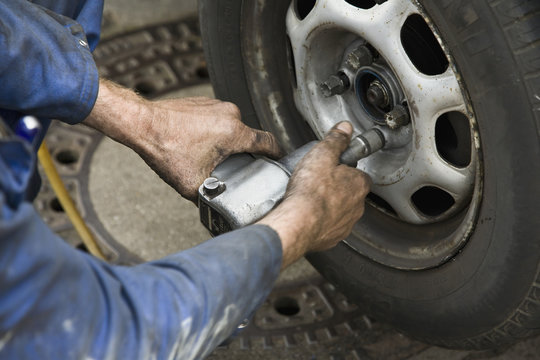 Close-up of mechanic's hands unscrewing a car wheel
