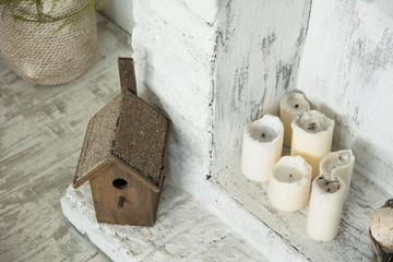 Birdhouse on floor next to the candles