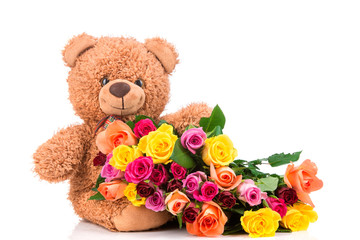 Bunch of mixed color roses and a teddy bear on white background