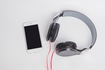 music concept - smartphone and headphones on white background,smartphone and headphones close-up