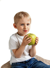 Happy cheerful boy eats the big apple, the child is the fruit gr