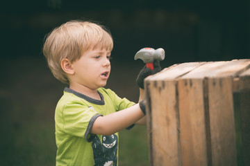 Boy with a hammer repairs wooden chest © Dziurek