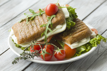 Sandwich with ham and tomatoes on wood background