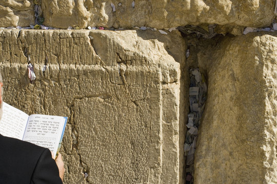 Man praying at the Wailing Wall, over the shoulder view, close-up