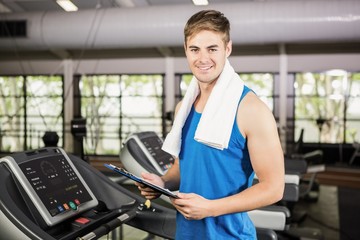 Fototapeta na wymiar Portrait of trainer holding clipboard on treadmill