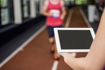 Trainer using a digital tablet while man running 
