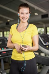 Portrait of woman listening to music on treadmill
