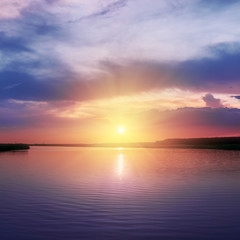 Fototapeta premium orange sunset over river in purple colors around