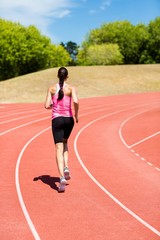 Obraz premium Rear view of female athlete running on the running track
