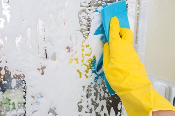 Housework concept. Person is cleaning mirror with rag.