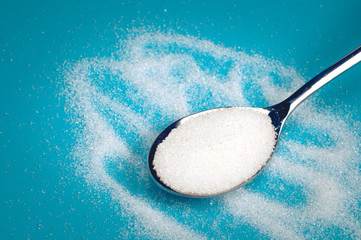 white Sugar spoon blue background.