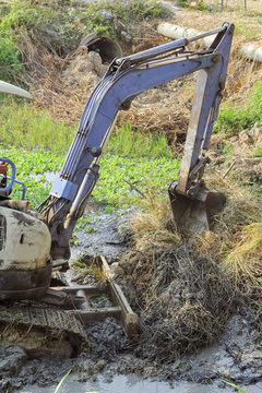 the backhoe was digging mud and weed on a river following heavy rain in Thailand.