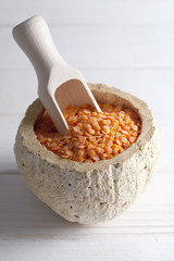 Red lentils in scoop and bowl on white planks