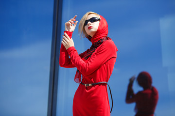 Woman in red on a background of glass walls reflecting blue sky