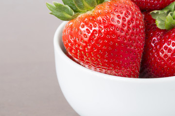 Big strawberry on white ceramic cup with copyspace on wooden tab