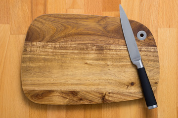 Knife on wooden cutting board on wooden background