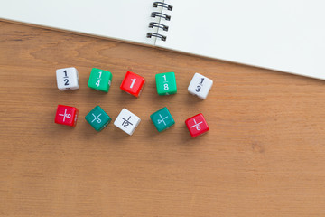 Color fraction dices, blank white notebook on wooden desk